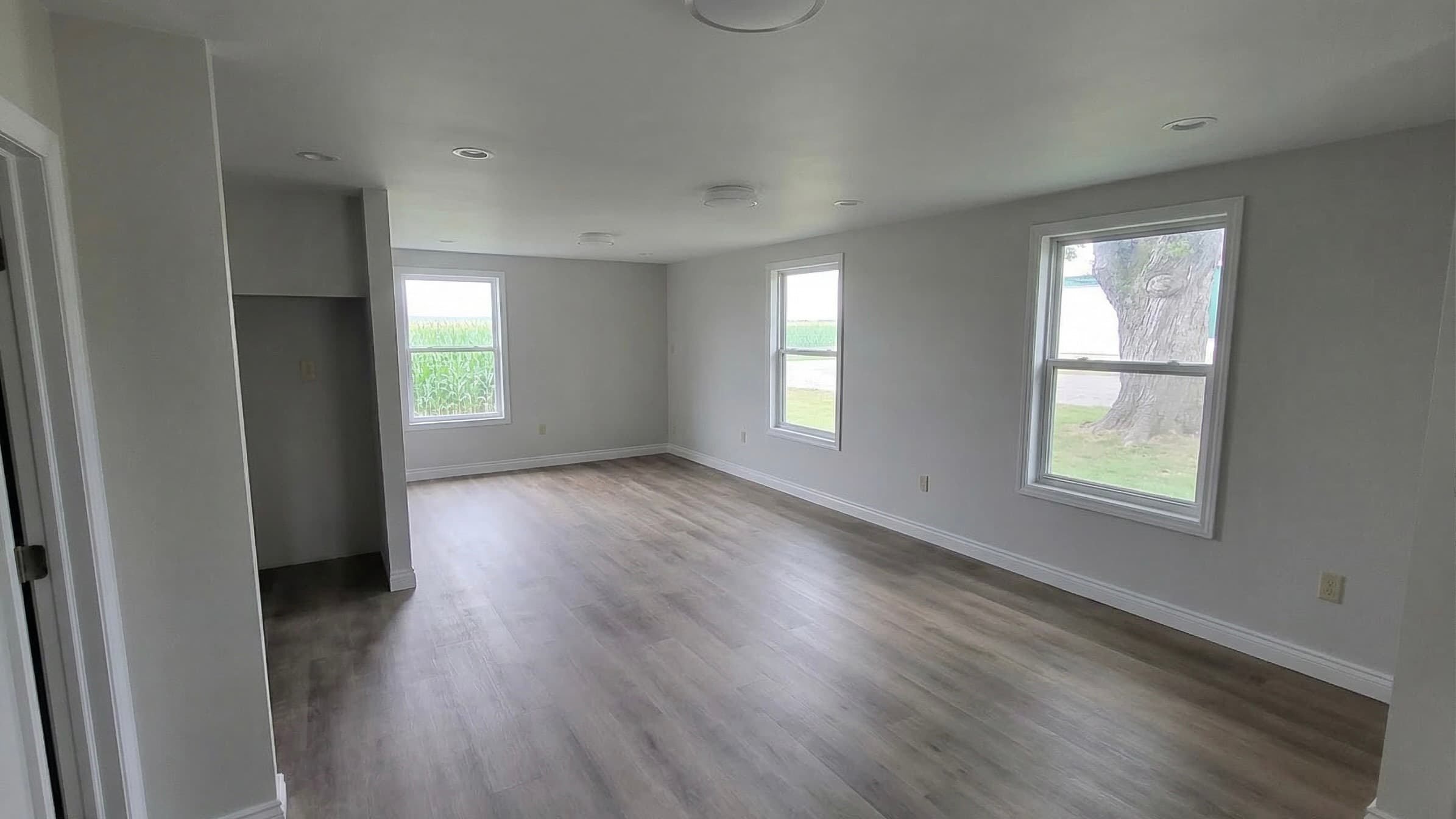 Bright, freshly finished living space with new plank flooring and white trim