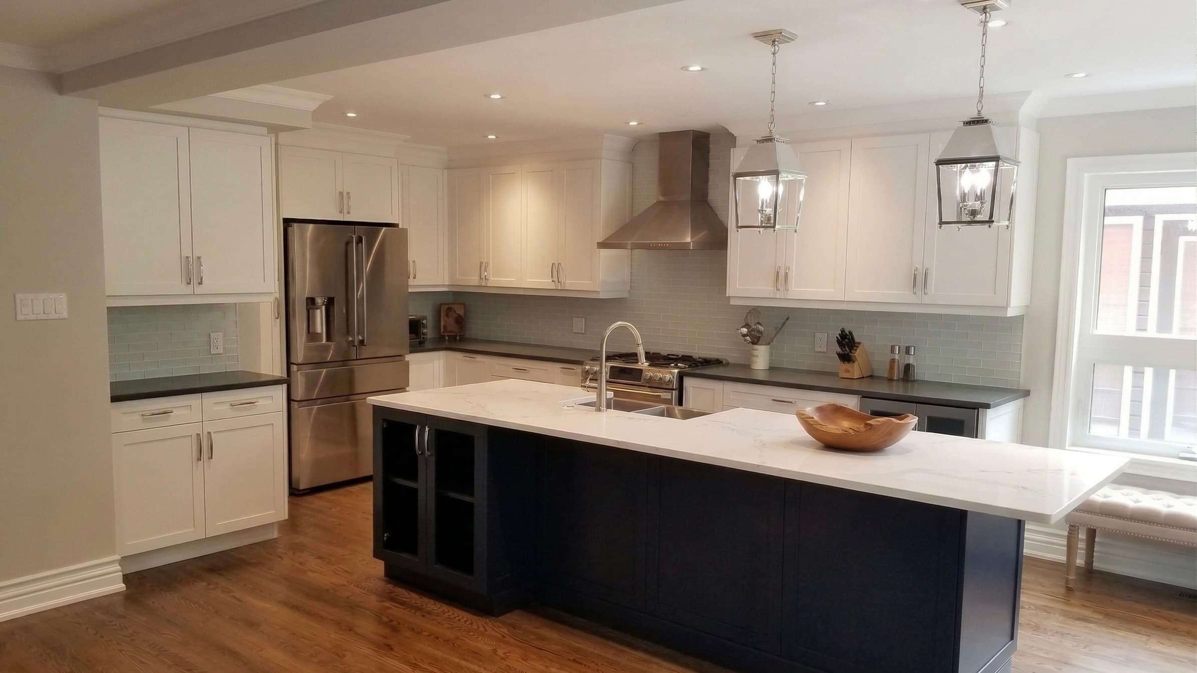 White shaker kitchen with a navy island, quartz countertop and pendant lights