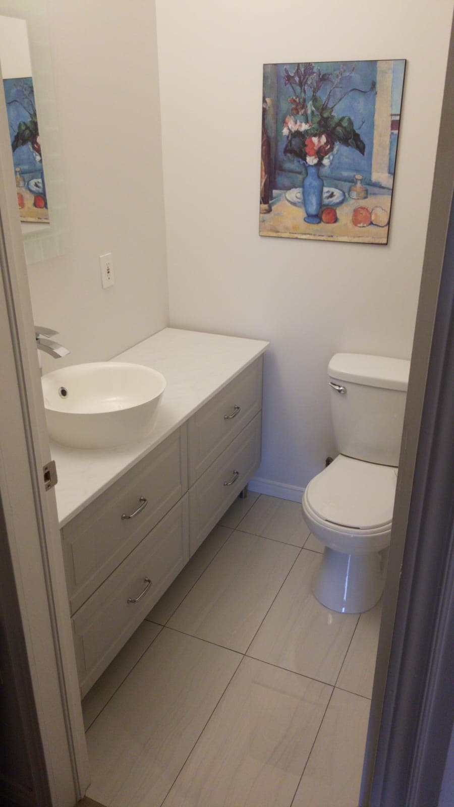 Renovated powder room with a vessel sink vanity and white tile floor