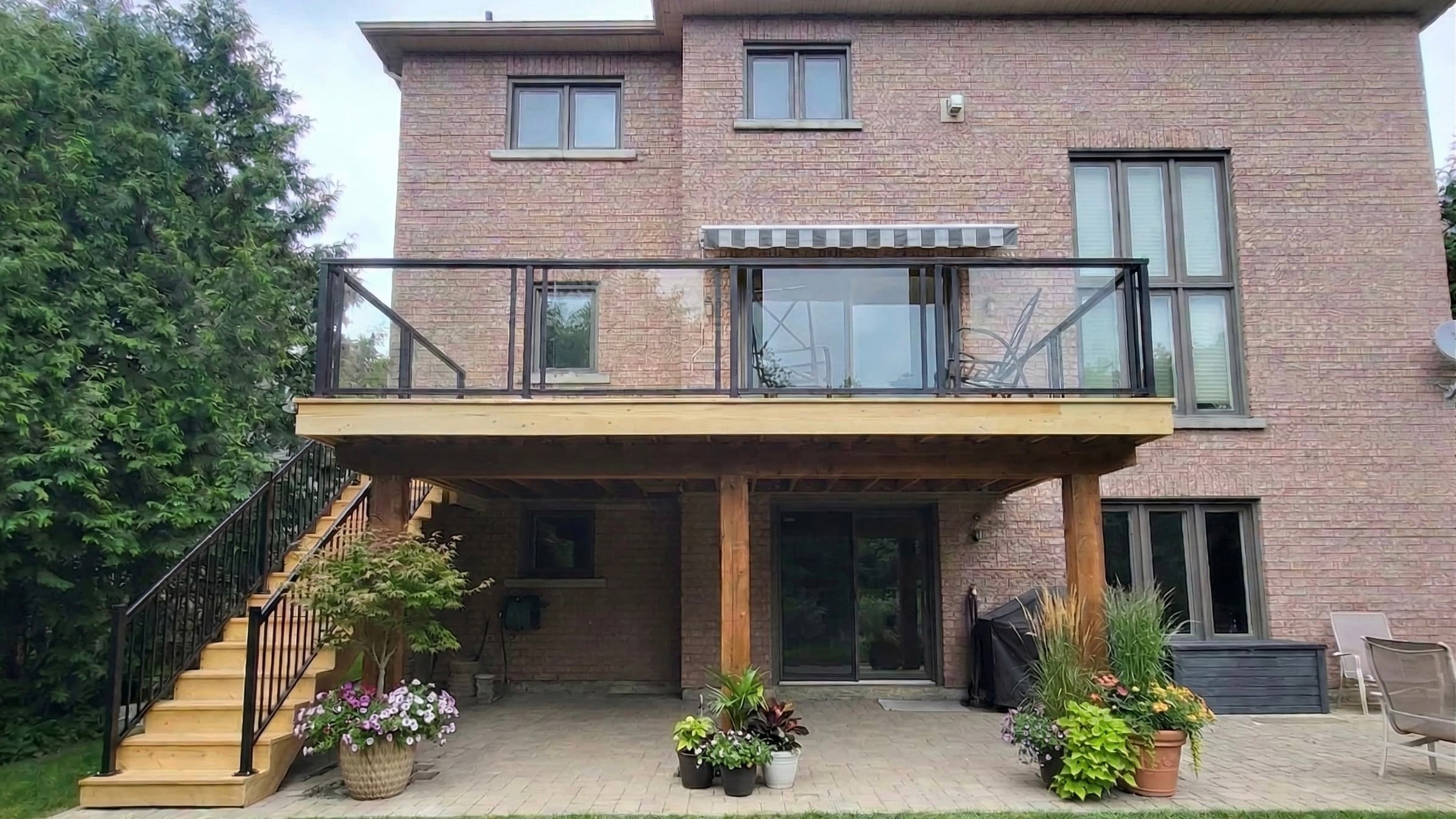 Raised rear deck with glass railing, timber posts and new stairs on a brick home